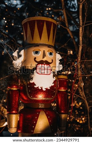 Christmas toy huge wooden Nutcracker with evening garland lights. Festive decor, New Year winter outdoor details. Vertical