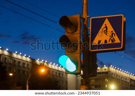Green signal light on the background of the evening city.
