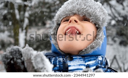 Young boy sticking out his tongue to catch snowflakes on a snowy day. Concept of playful winter activities
