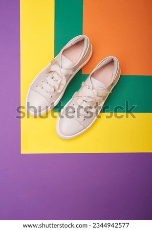 A pair of modern casual beige sneakers on a multicolor background with copy space. Creative fashion photography