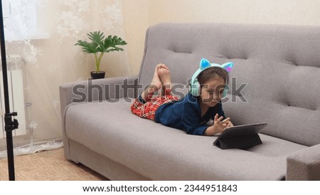 Cute little girl with headphones and tablet listening to audiobook at home, watching cartoons, playing games, chatting online. interactive online learning for kids.