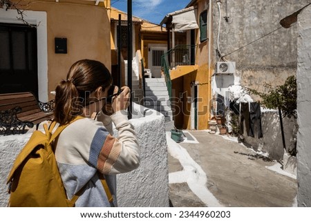 Female tourist taking pictures of a street in Corfu, Greece