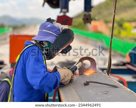 welder in blue suit Wearing a welding mask, welding steel at a construction site Royalty-Free Stock Photo #2344962491