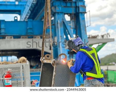 welder in blue suit Wearing a welding mask, welding steel at a construction site Royalty-Free Stock Photo #2344963005