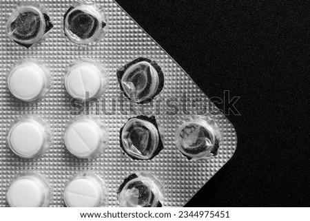 A fragment of a gray, metallized, partially used blister with medical pills on a black background. Photo. Macro. Close-up
