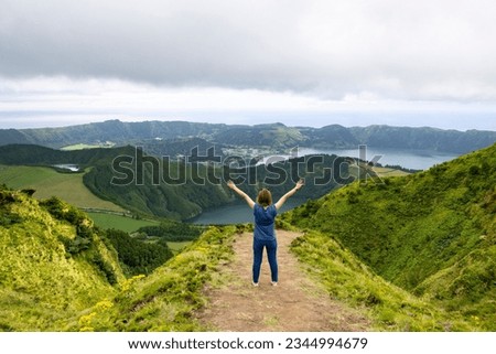 Young woman with open arms enjoying the freedom and the beautiful landscape view of the Twin Lakes in Sete Cidades in the island of Sao Miguel, Azores, Portugal Royalty-Free Stock Photo #2344994679