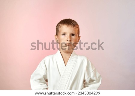 On a gradient colored background, a cute pensive child in karategi Royalty-Free Stock Photo #2345004299