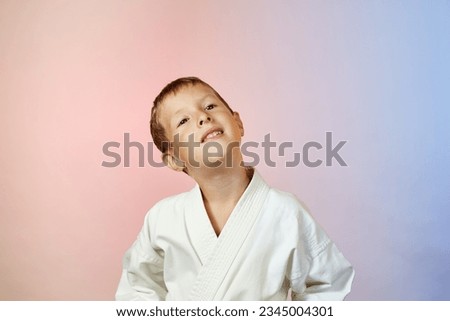 On a gradient colored background, a cute pensive child in karategi Royalty-Free Stock Photo #2345004301