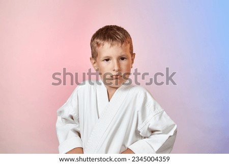 On a gradient colored background, a pensive child in karategi Royalty-Free Stock Photo #2345004359