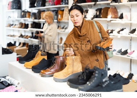Asian woman who came to a shoe store for shopping chooses Timberland style autumn boots Royalty-Free Stock Photo #2345006291
