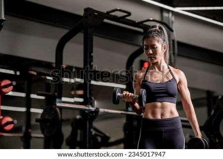 Portrait of a young Asian woman, good looking, shapely, in a black dress. She's working exercise fitness out in a world-class gym, work hard.