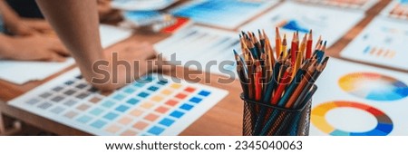 Graphic designer brainstorm logo and graphic art at busy creative studio workshop. Experiment and brainstorm color palette and pattern at workspace table for creative design. Panorama shot. Scrutinize