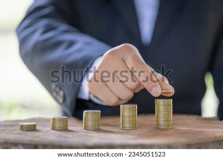 hand put money coins to stack of coins. Invest your money to get in come,growing business and future concept