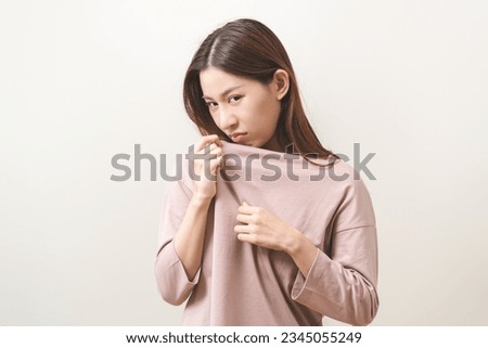 Bad smelling, deodorant asian young woman smell stink, breathing nose smelly on shirt dirty stinky laundry, disgusting from clothes after washed, smelly armpit underarm Medical health, skin body care. Royalty-Free Stock Photo #2345055249