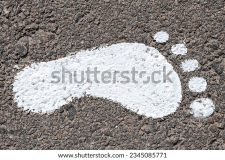 Bare footprint on asphalt. White paint imprint of a human footprint of bare feet on an asphalt road. White foot print.