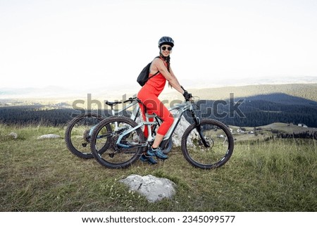 Pretty woman riding her electric mountain bike in the mountains