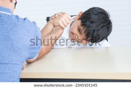 Selective focus on hands of Indian child son and father, have fun playing, competing in arm wrestling together on table at home. Education, Family relationship, Activity Concept