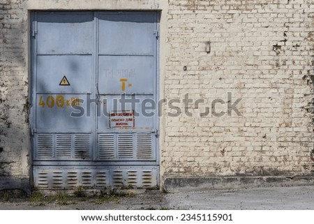 An iron door to an old brick electrical substation with a warning sign in Russian: "Do not enter! Danger to life!"