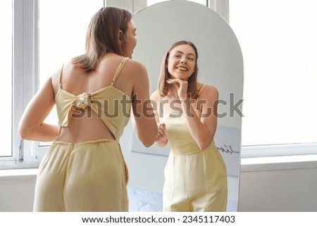 Young woman looking in mirror at home