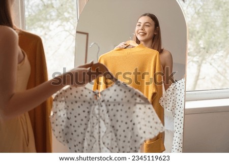 Young woman choosing clothes in front of mirror at home Royalty-Free Stock Photo #2345119623