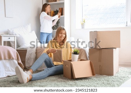 Female student unpacking things in dorm room on moving day Royalty-Free Stock Photo #2345121823
