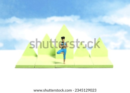 Creative miniature people toy figure photography. Sticky notes installation. A woman doing outdoor yoga with mountain hill and sky background. Image photo
