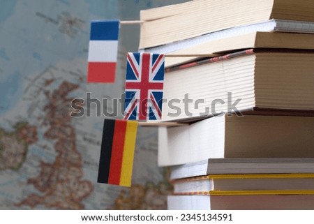 Stack of books with country flags on background of map, foreign language learning concept Royalty-Free Stock Photo #2345134591