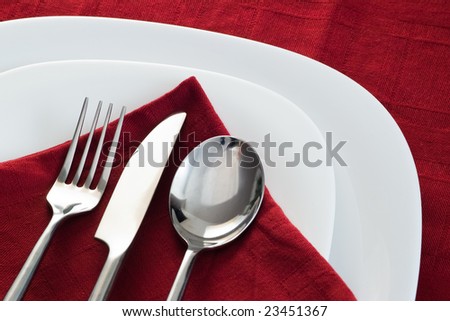 fork knife and spoon on white plate and dark red napkin Royalty-Free Stock Photo #23451367