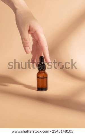 product package with serum and a woman hand in studio on a beige background to promote an antiaging treatment. Skincare, beauty and bottle with a female model. Mockup Royalty-Free Stock Photo #2345148105