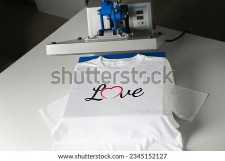 Printing logo. Heat press with t-shirt on white table