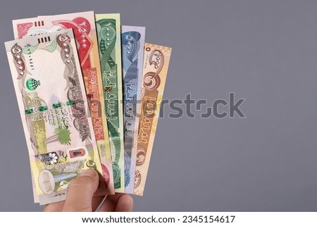 Iraqi money - dinar in the hand on a gray background Royalty-Free Stock Photo #2345154617