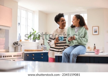 Mother Talking With Teenage Daughter At Home As She Checks Social Media On Mobile Phone Royalty-Free Stock Photo #2345159081