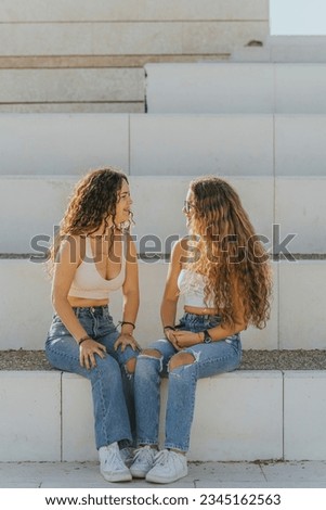 Young women girls smiling with curly hair posing for photographs in green areas and parks. Girls models together smiling.