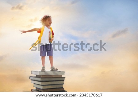 Children go back to school. Start of new school year after summer vacation. Boy with backpack and books on pile of books on first school day. Beginning of class. Education for preschool kids. Royalty-Free Stock Photo #2345170617