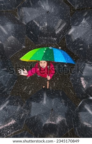Happy young girl under colorful umbrella in dark crowd in autumn rain. Happiness and optimism concept. Joy and hope in difficult situations. Problem solving and creativity. Stand out and be unique. Royalty-Free Stock Photo #2345170849