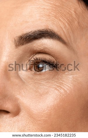 Cropped portrait of beautiful middle-aged woman eyes and brows. Old lady looking away. One eye. Wrinkles in periorbital zone. Concept of fashion, beauty, spa, cosmetology, skincare. Royalty-Free Stock Photo #2345182235