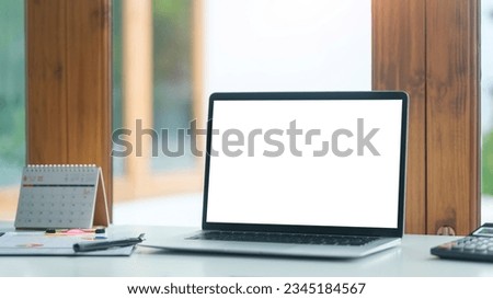 Laptop computer with empty display and cup of coffee on white table in bright office interior.