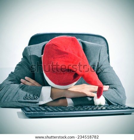 a man in suit with a santa hat sleeping in his desk after an office christmas party