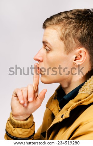 Handsome man with finger on lips asking for silence