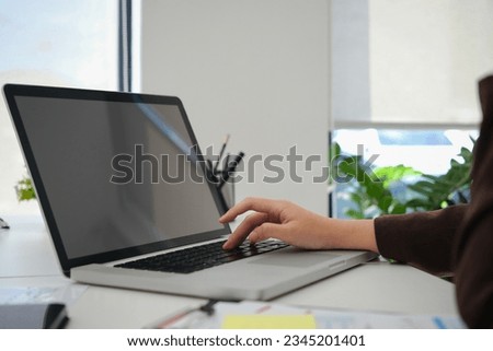 Closeup view female entrepreneur searching online information on laptop, working with reports at office