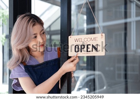 Happy young business owner waitress standing at restaurant coffee shop store entrance to welcome customer, Small business  Young Asian owner retail, coffee shop with sign of open board