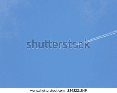White airplane and contrail diagonally in picture against blue sky