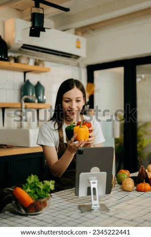 Young woman video blogger cooking at the kitchen and filming healthy food concept Royalty-Free Stock Photo #2345222441