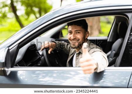 Young handsome man smiling happy doing ok sign driving car.