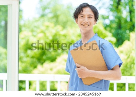 portrait of a male asian doctor in scrubs in front of a park Royalty-Free Stock Photo #2345245169