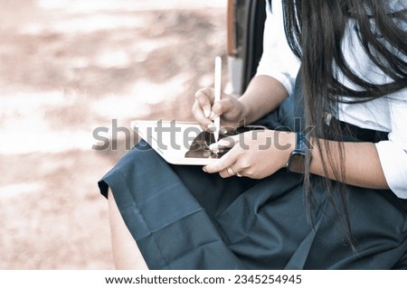 Young girls in student uniform using the mouse-pen draft to small grass flowers are placed on the surface of computer tablets in art hour.