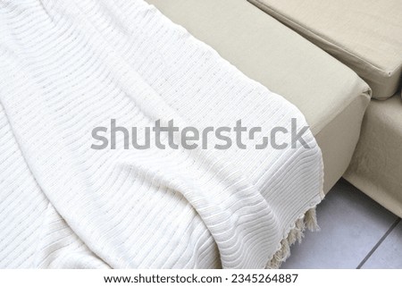 a hand-knitted yarn blanket on a beige couch Royalty-Free Stock Photo #2345264887