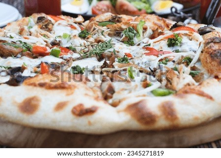 Various ingredients are served in a pizza such as mozzarella cheese, onions, red peppers, green peppers, mushrooms, shredded chicken, oregano leaves. 