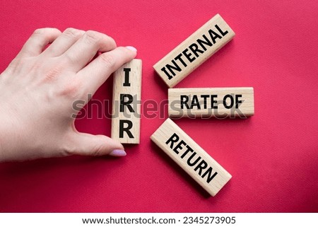 IRR - Internal Rate of Return symbol. Concept word IRR on wooden cubes. Businessman hand. Beautiful red background. Business and IRR concept. Copy space.