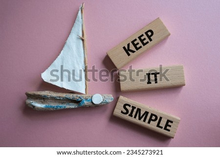 Keep it Simple symbol. Concept words Keep it Simple on wooden blocks. Beautiful pink background with boat. Business and Keep it Simple concept. Copy space.